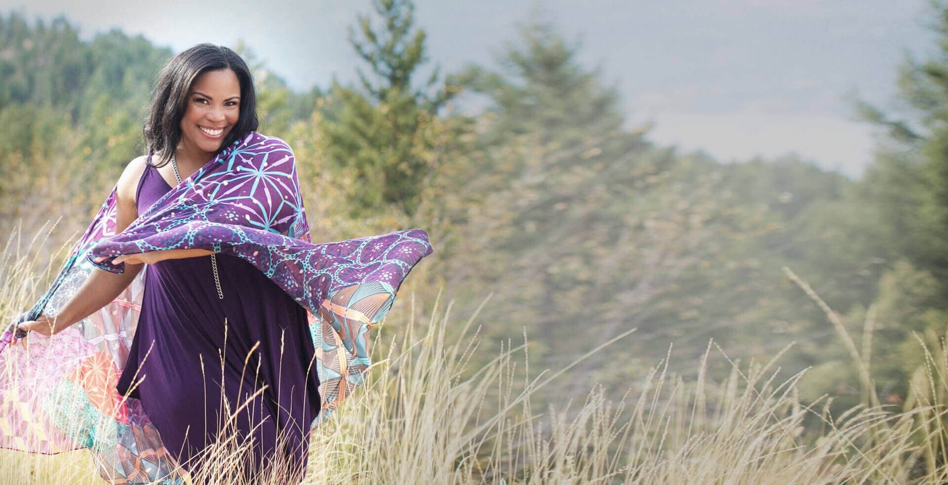Patty Staco outdoors in a field, holding a flowing purple scarf